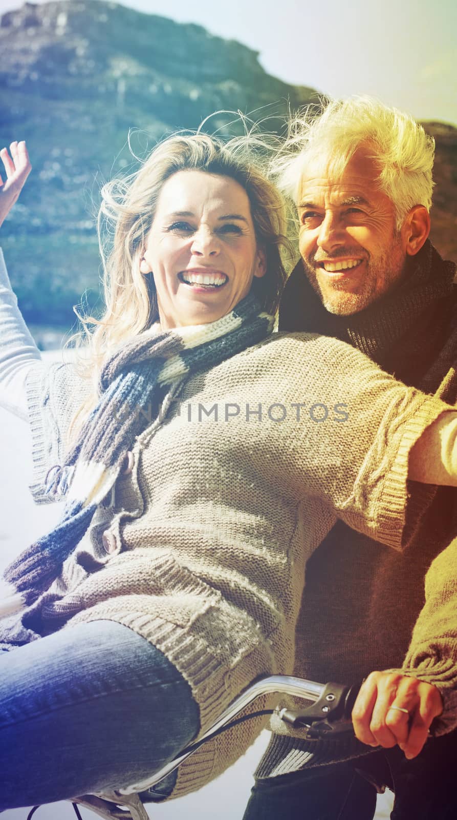 Carefree couple going on a bike ride on the beach on a bright but cool day