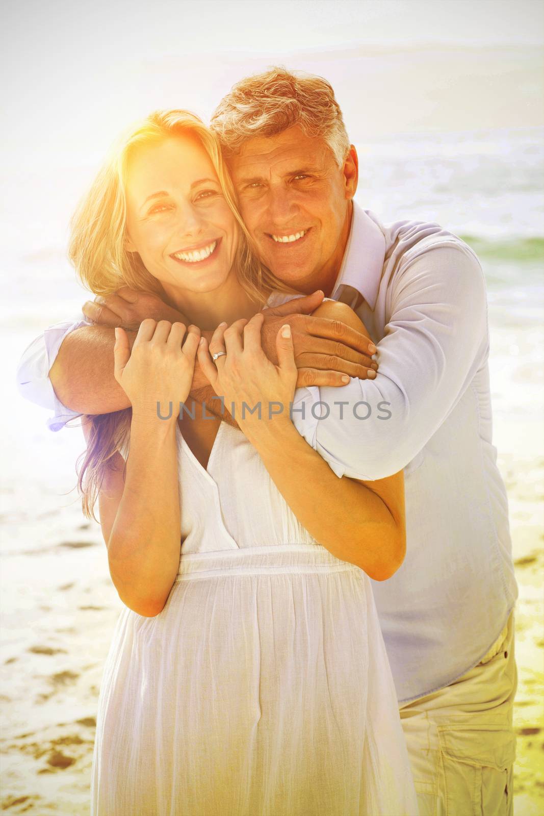 Happy couple hugging each other by the sea at the beach