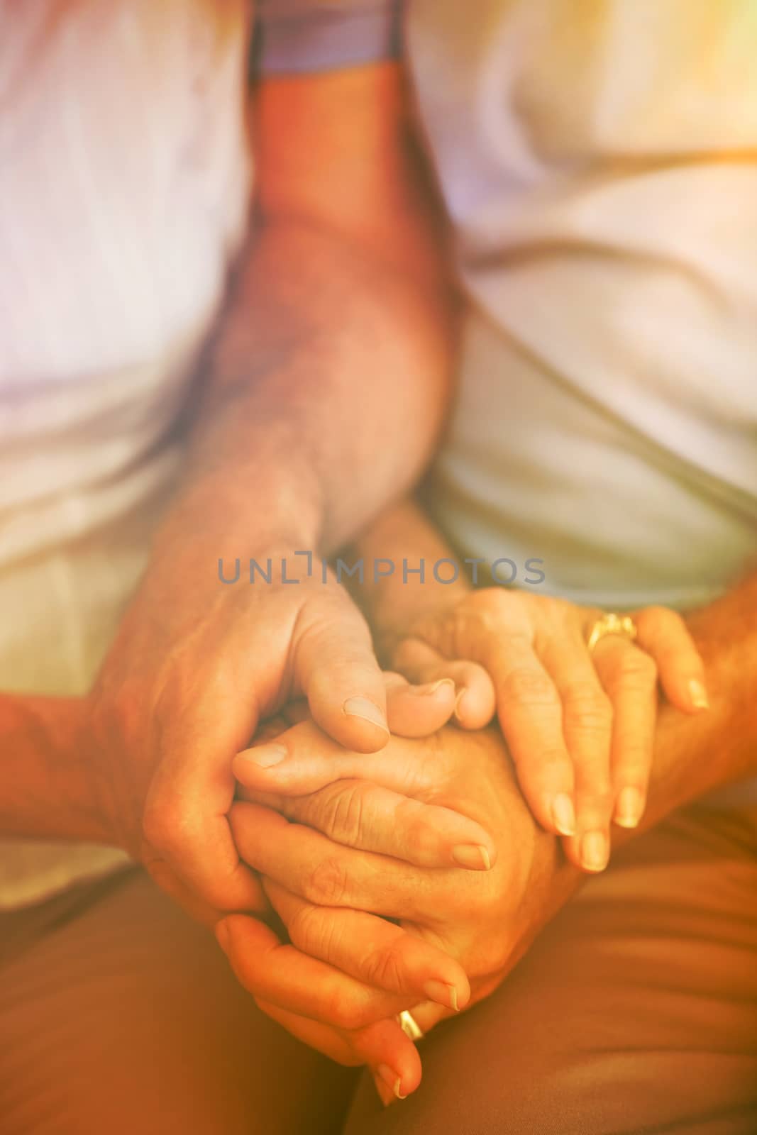 Cropped image of couple holding hands while sitting