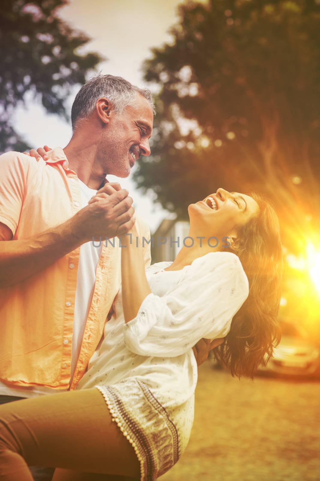 Playful couple dancing against trees in city