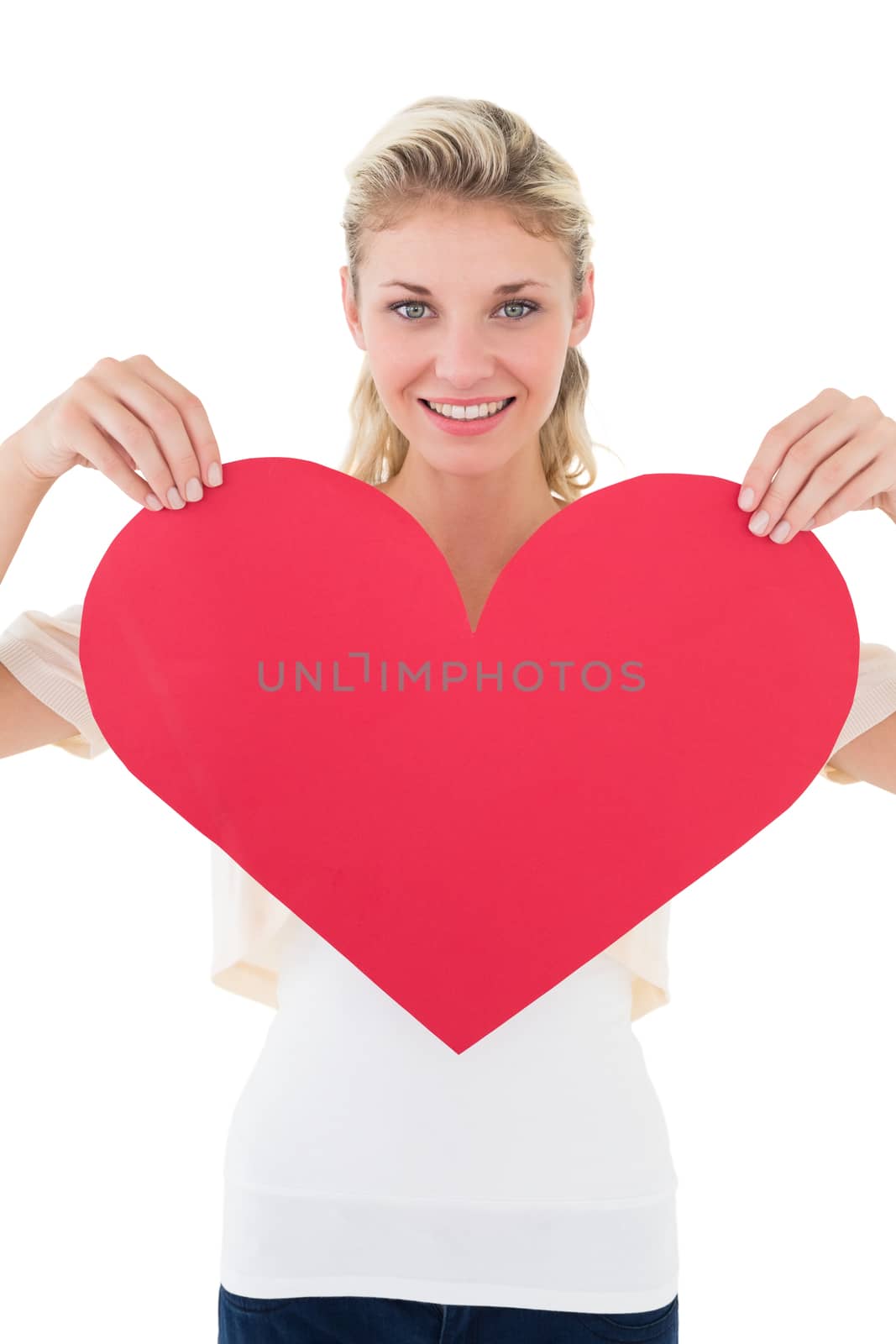 Portrait of smiling young woman holding heart over white background