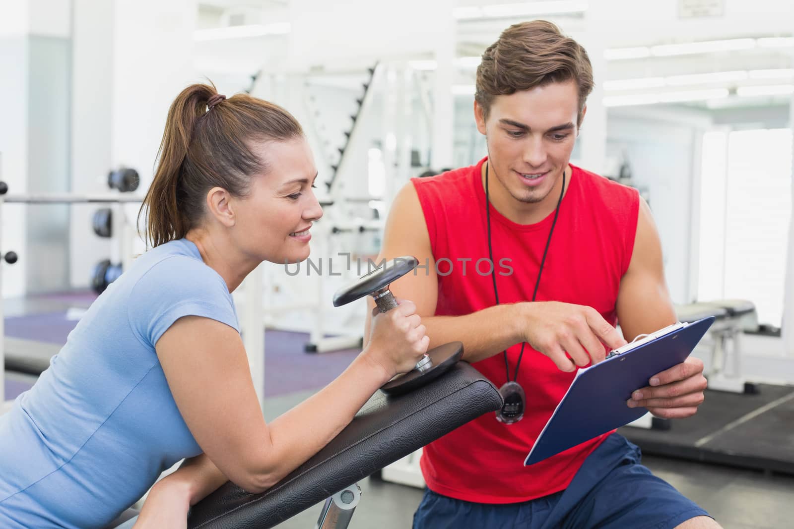 Personal trainer working with client holding dumbbell at the gym