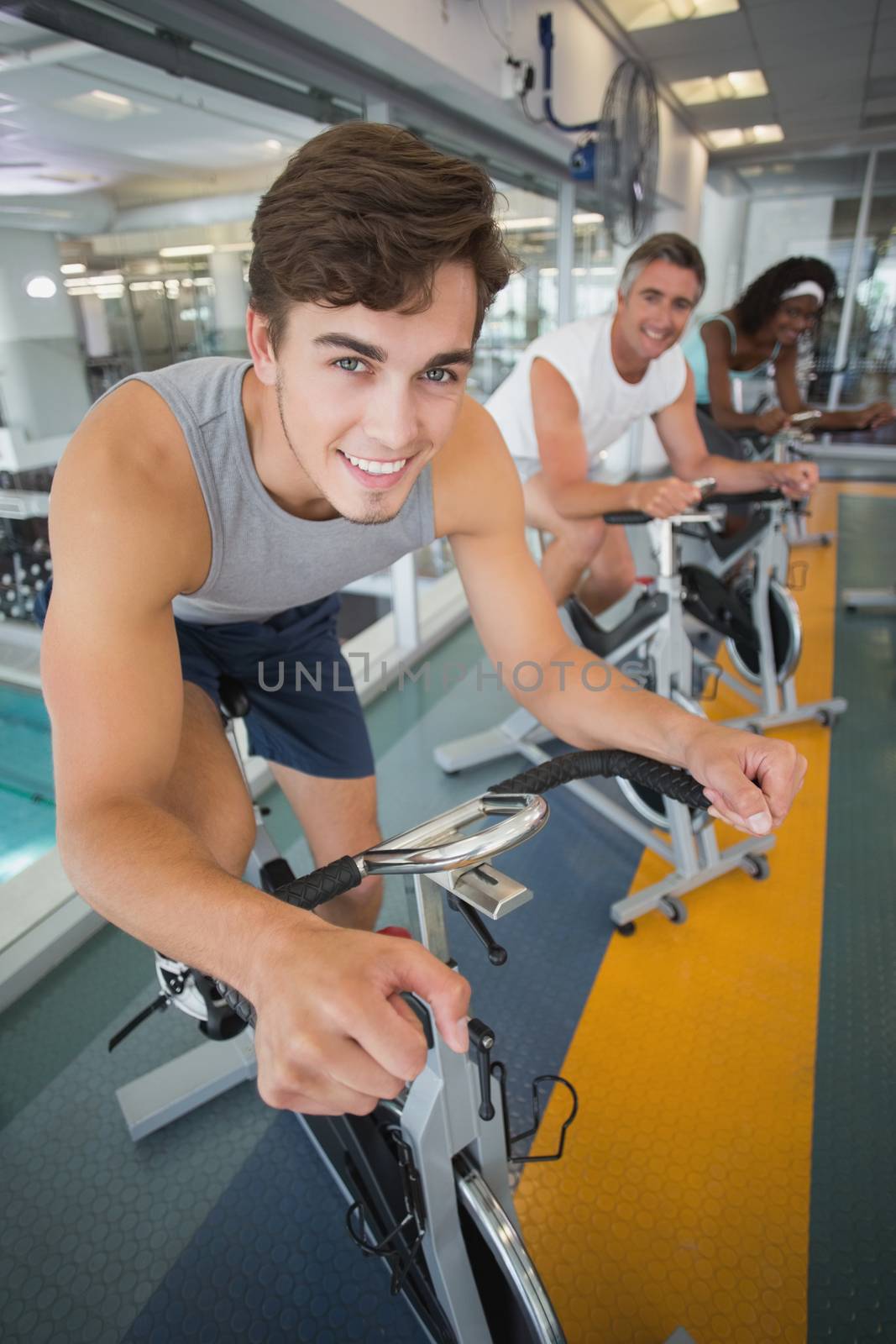 Three fit people working out on exercise bikes at the gym