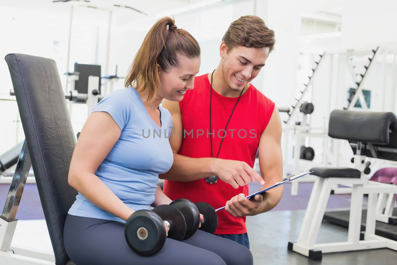 Personal trainer working with client holding dumbbell at the gym