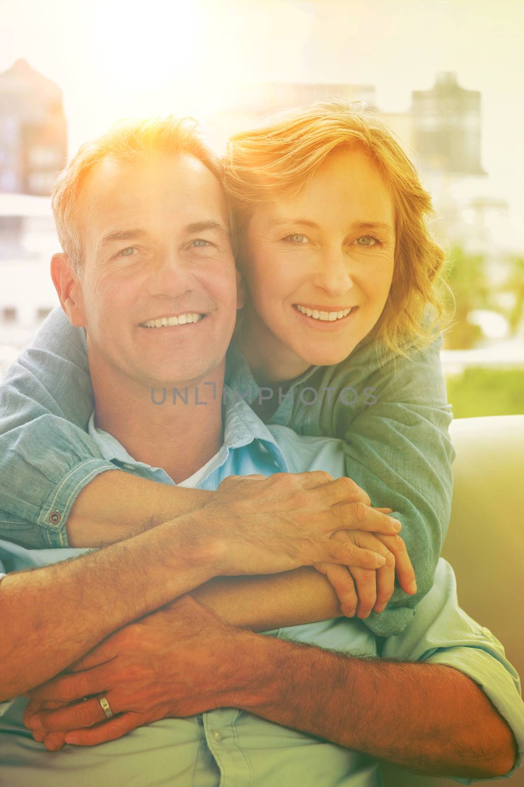 Portrait of happy woman hugging her husband  from behind at home