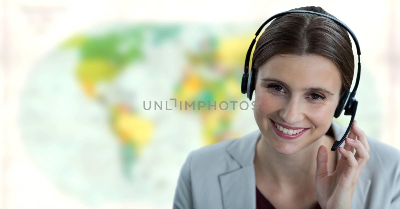 Travel agent woman wearing headset in front of world map by Wavebreakmedia