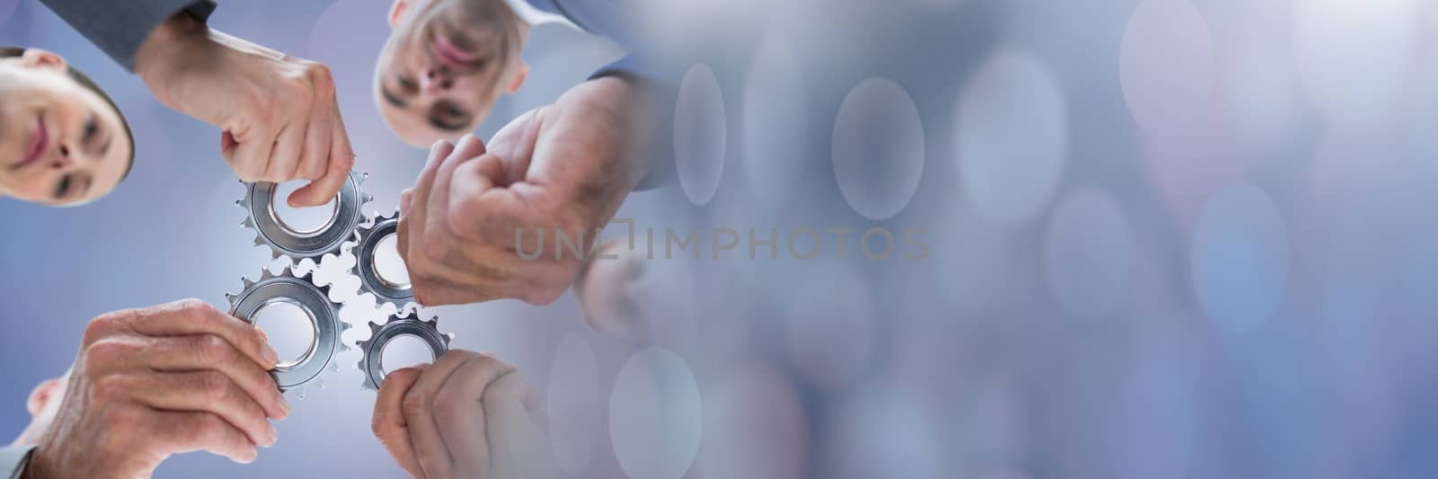 Digital composite of Teamwork transition with business people holding gear cogs