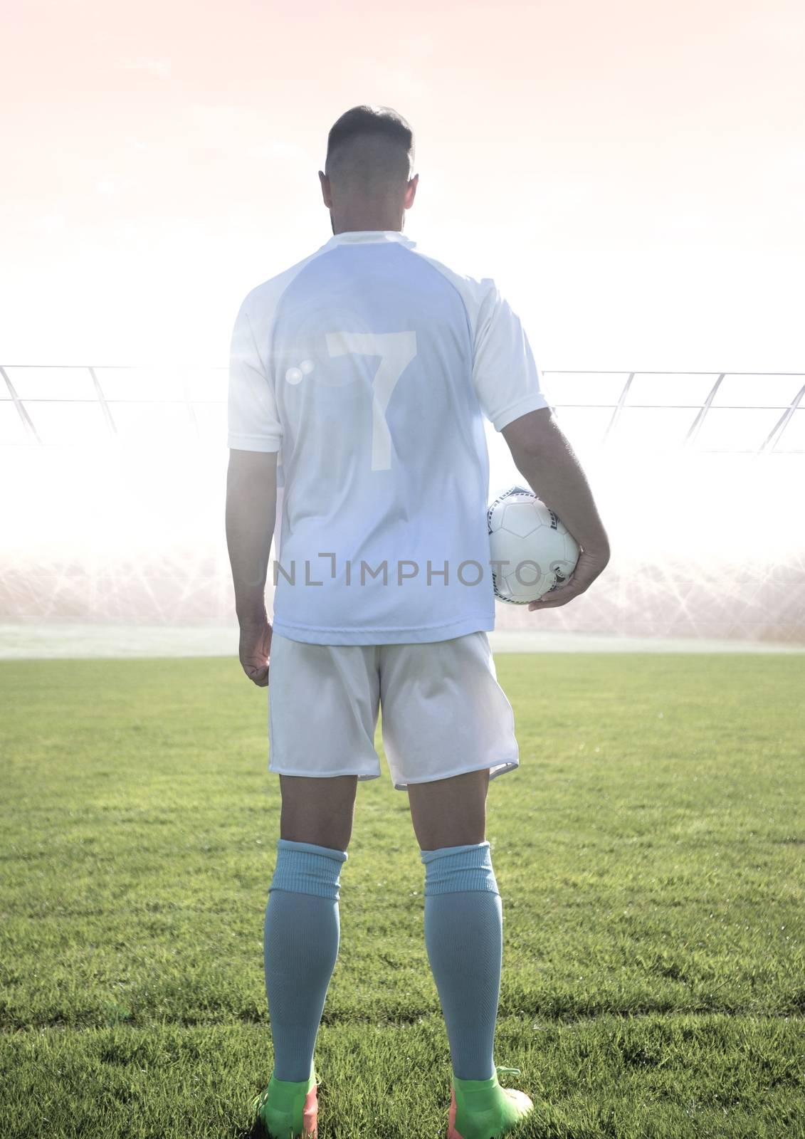 Digital composite of Soccer player on grass with stadium