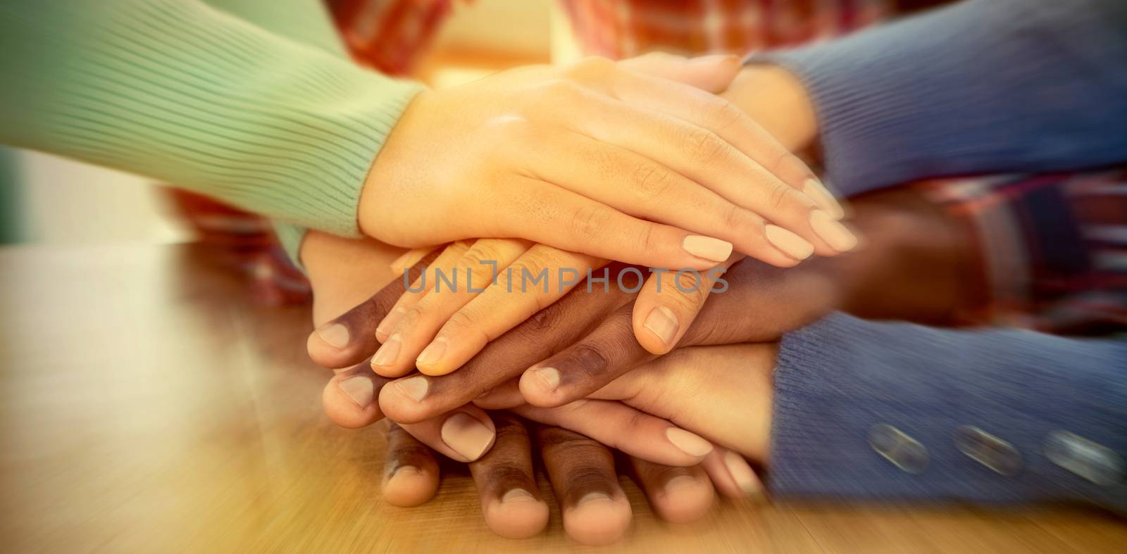Business people with stacked hands on desk  by Wavebreakmedia