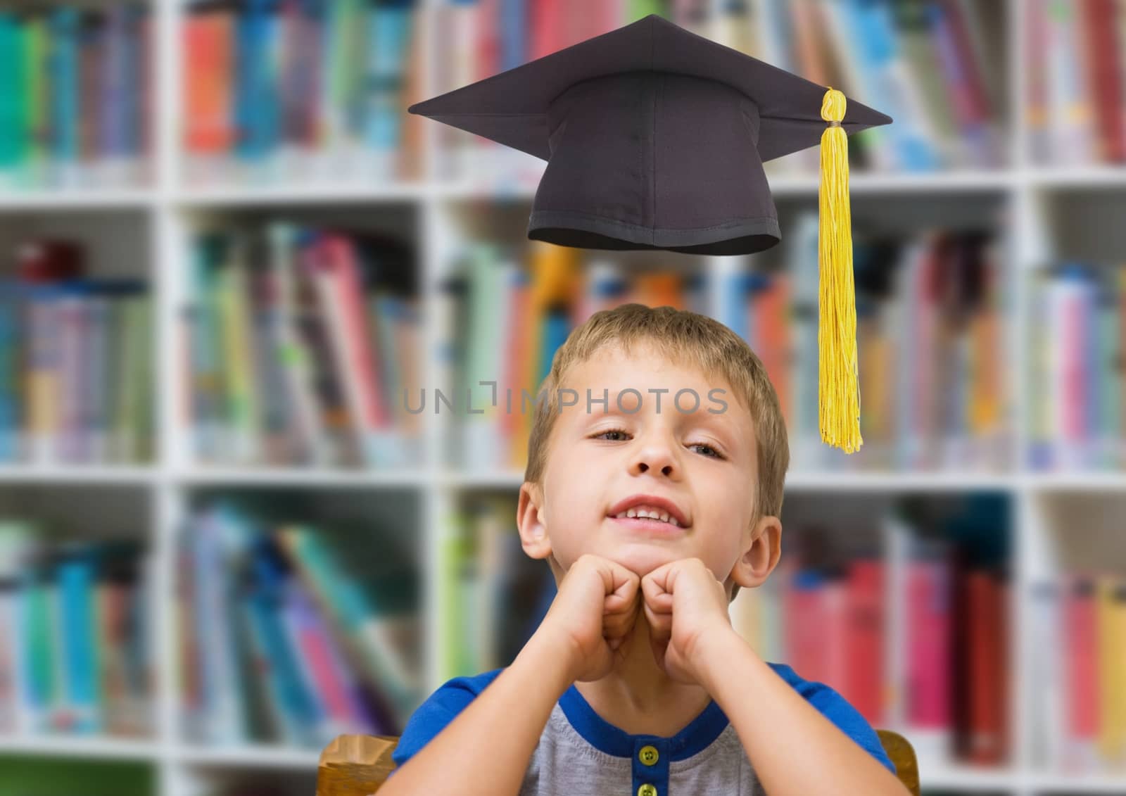 School boy in education library with graduation hat by Wavebreakmedia