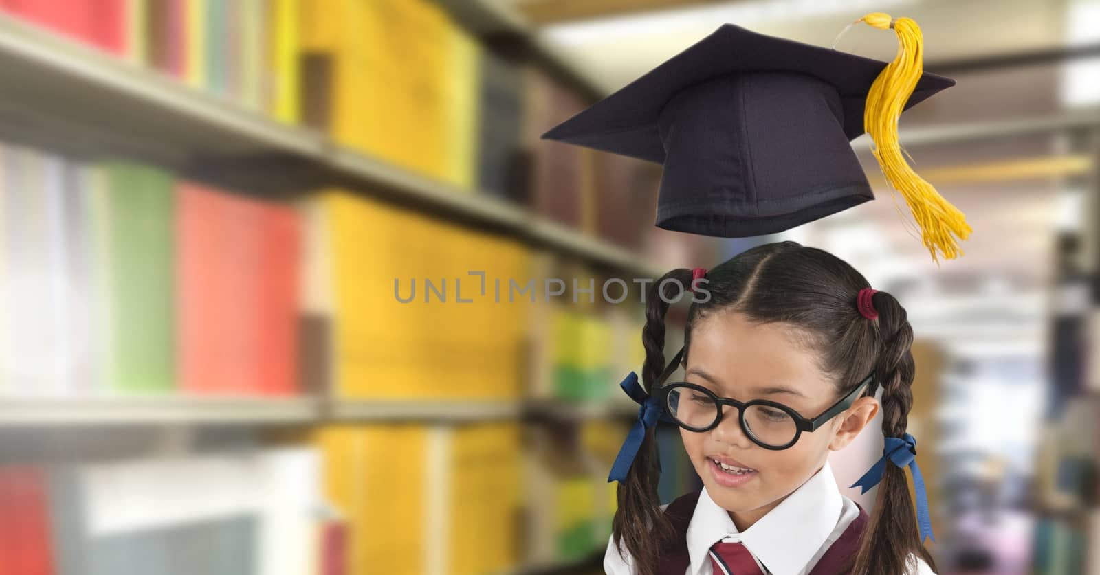 School girl in education library with graduation hat by Wavebreakmedia