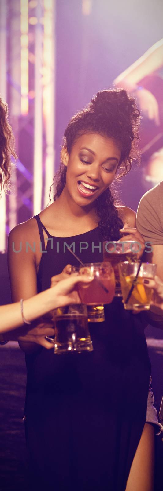 Happy young friends toasting drinks with performer singing in background at nightclub