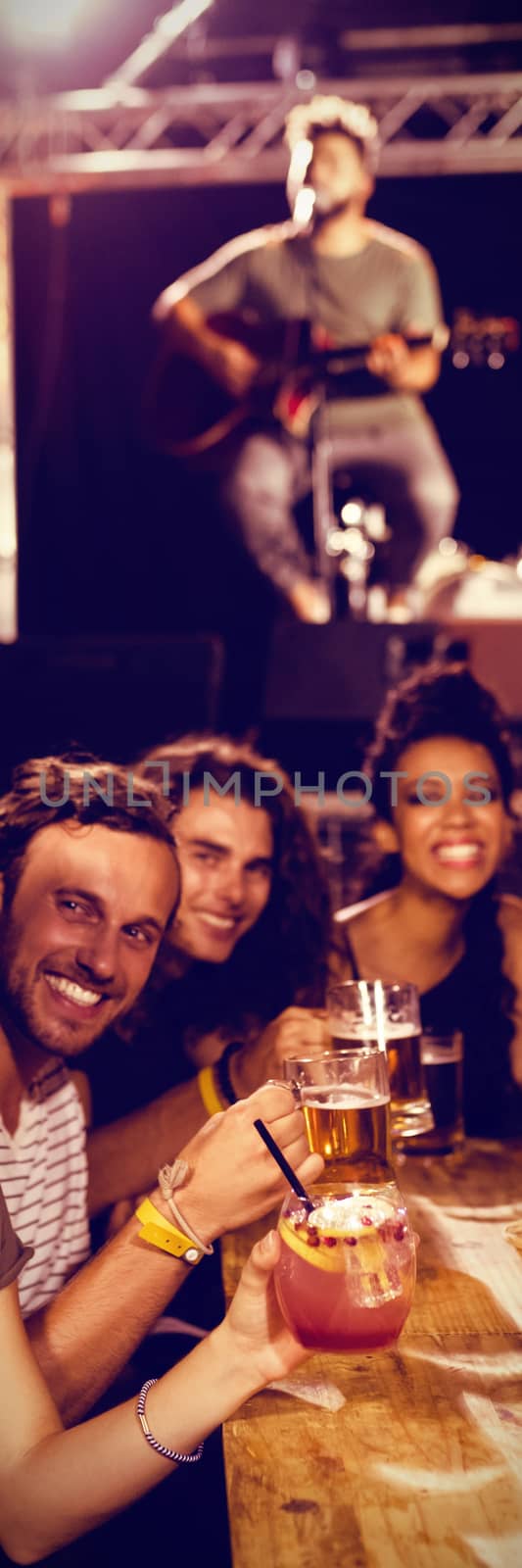 Cheerful friends taking selfie at table while performer on stage