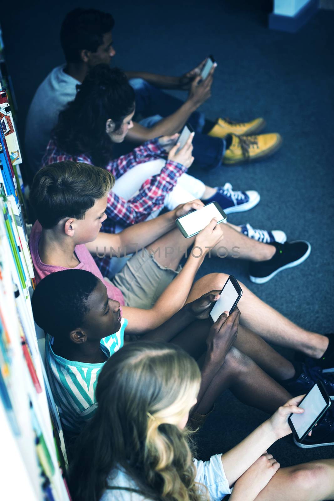 Students using mobile phone in library at school