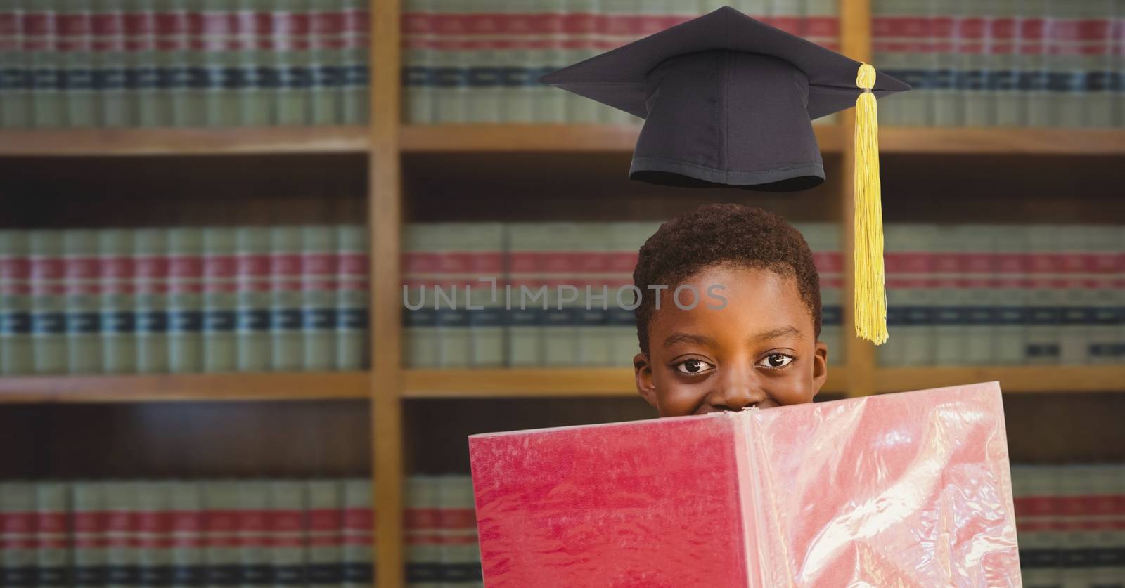 Boy with graduation hat in education library by Wavebreakmedia