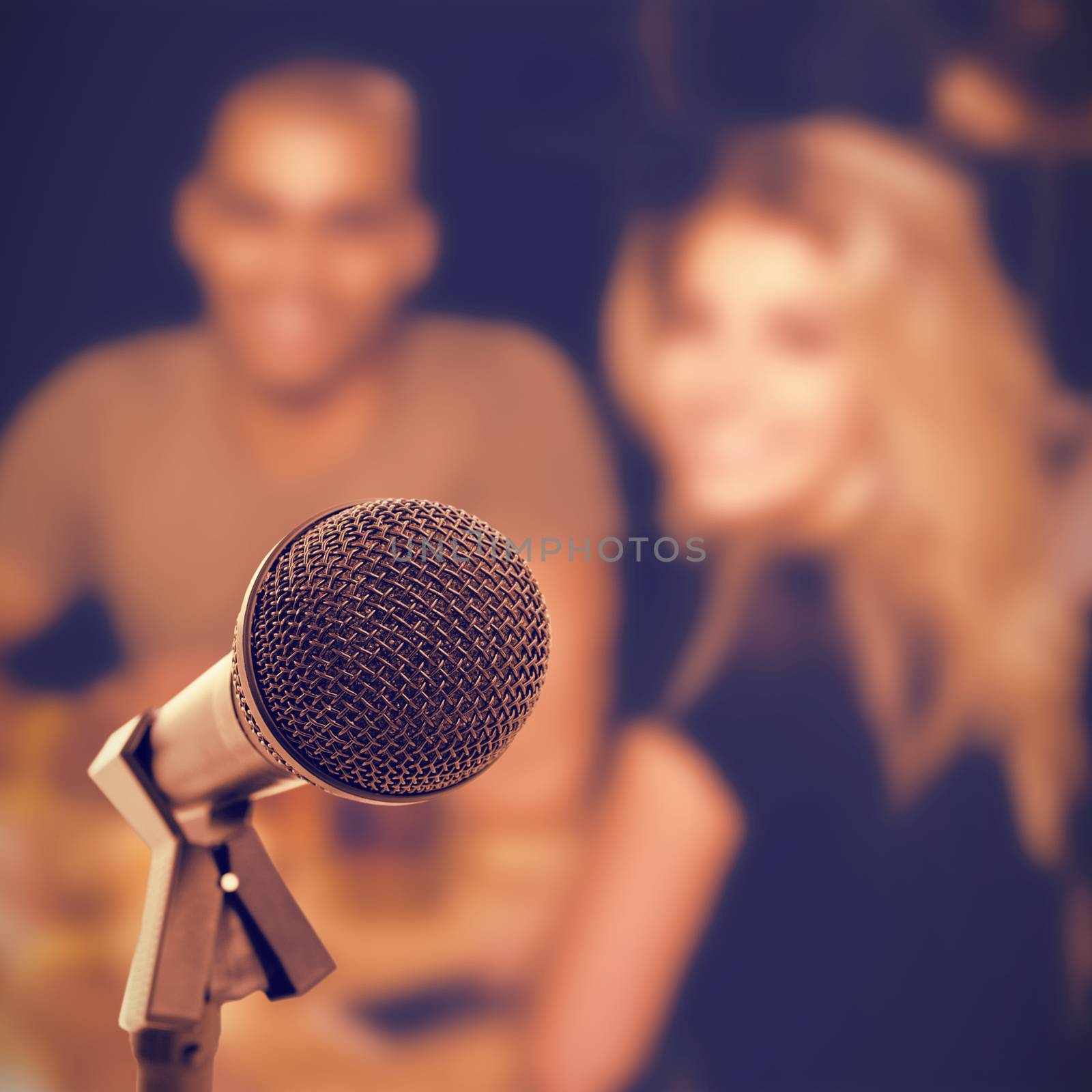 Microphone with stand against smiling young friends sitting at nightclub