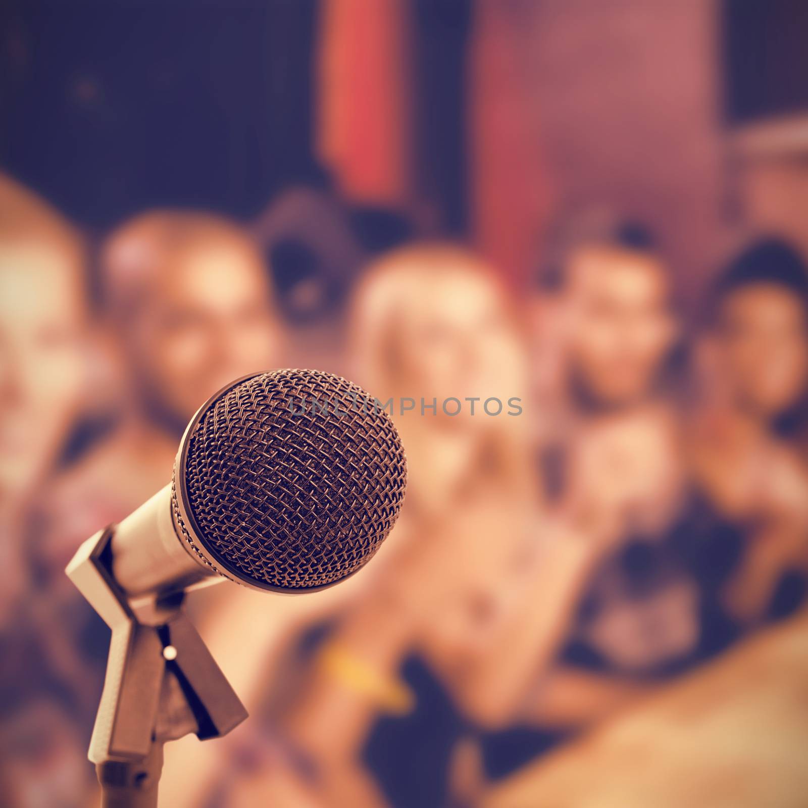 Microphone with stand against happy friends sitting at table in nightclub