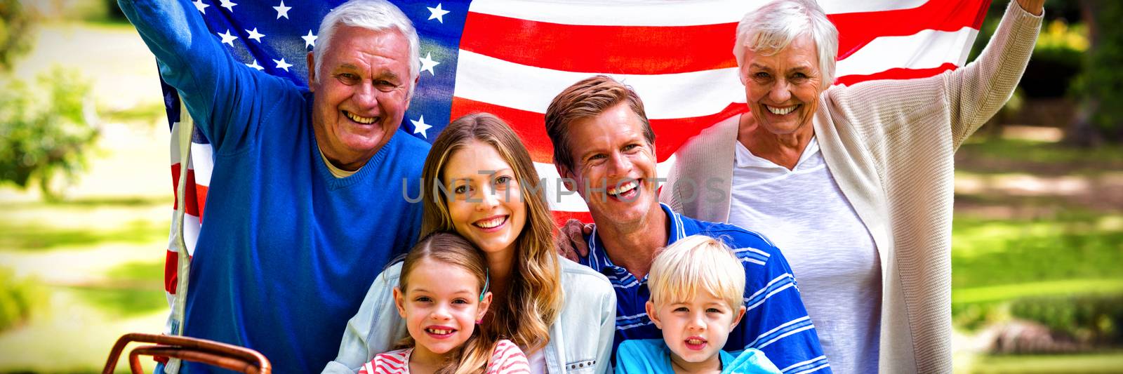 Multi-generation family holding american flag in the park by Wavebreakmedia