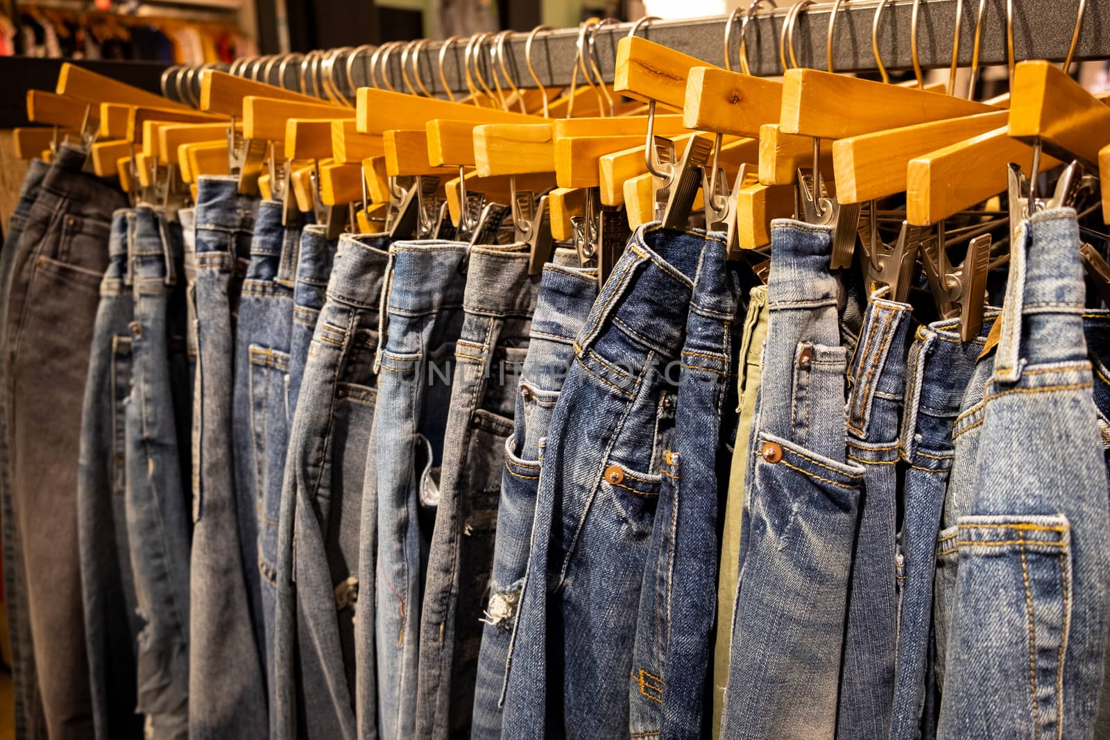 Fashion blue pants and jeans hang on the rack in clothing store. Sale, shopping, fashion, style concept.