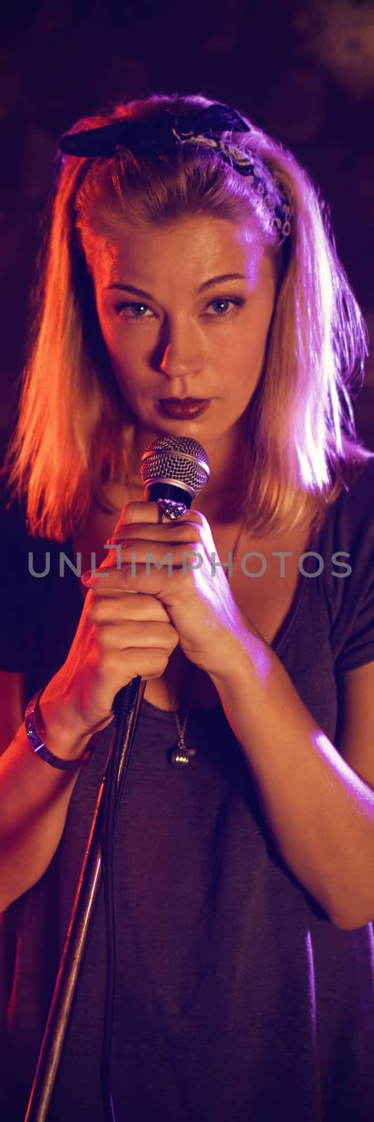 Portrait of confident female singer with drummer performing on illuminated stage in nightclub