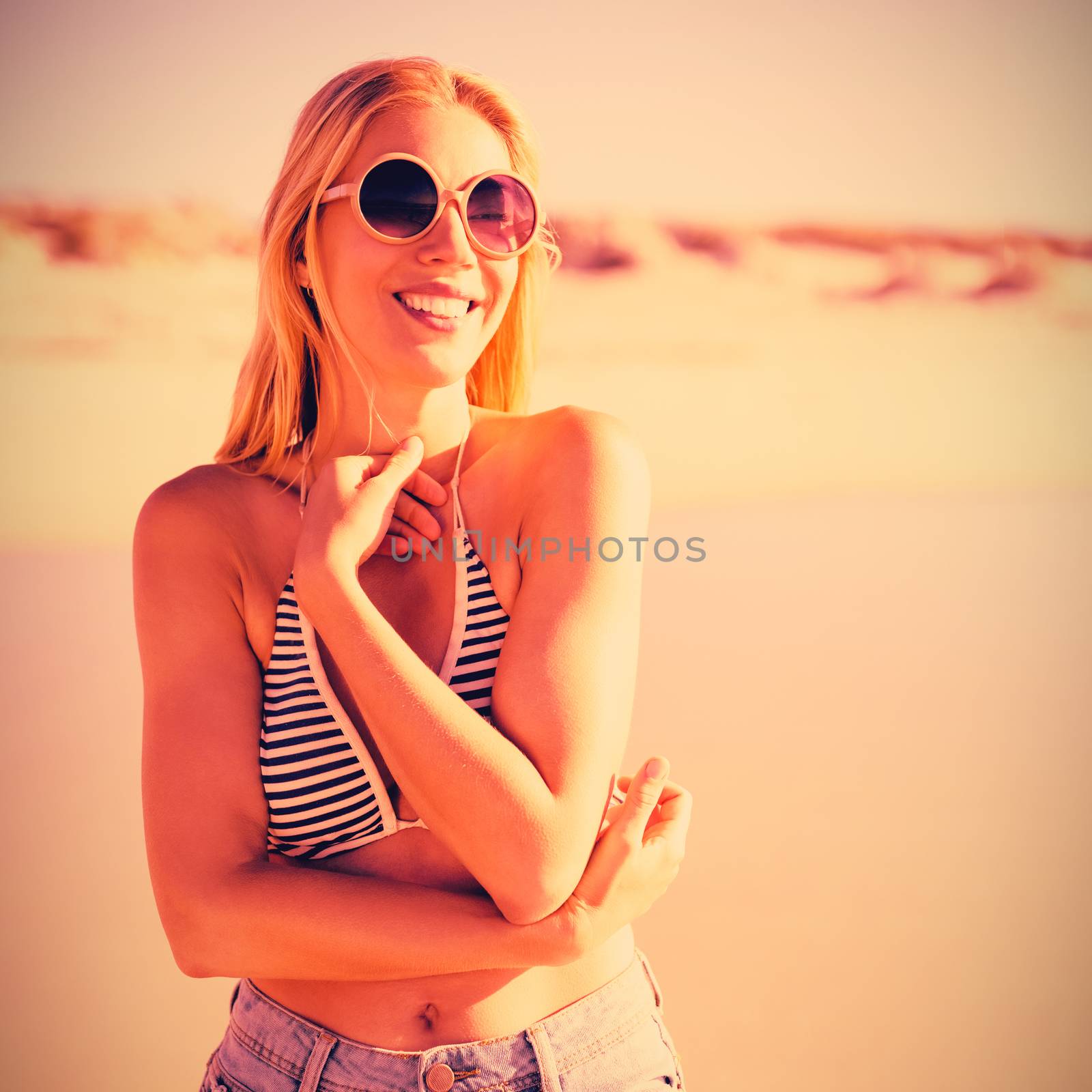 Happy young woman wearing sunglasses at beach by Wavebreakmedia