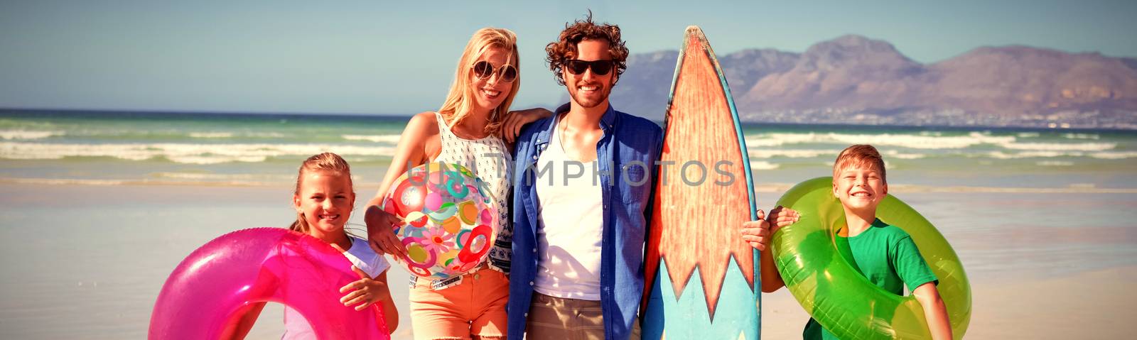 Portrait of happy family standing at beach during sunny day