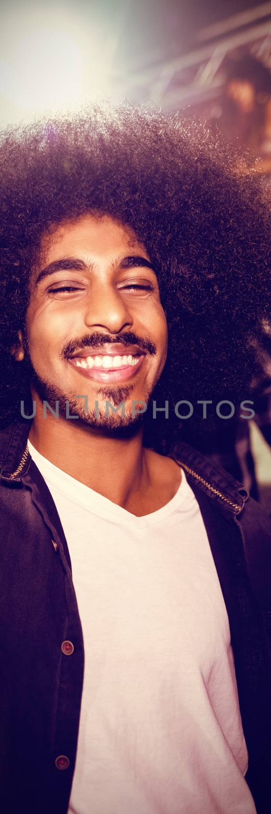 Happy young man with drink dancing in nightclub