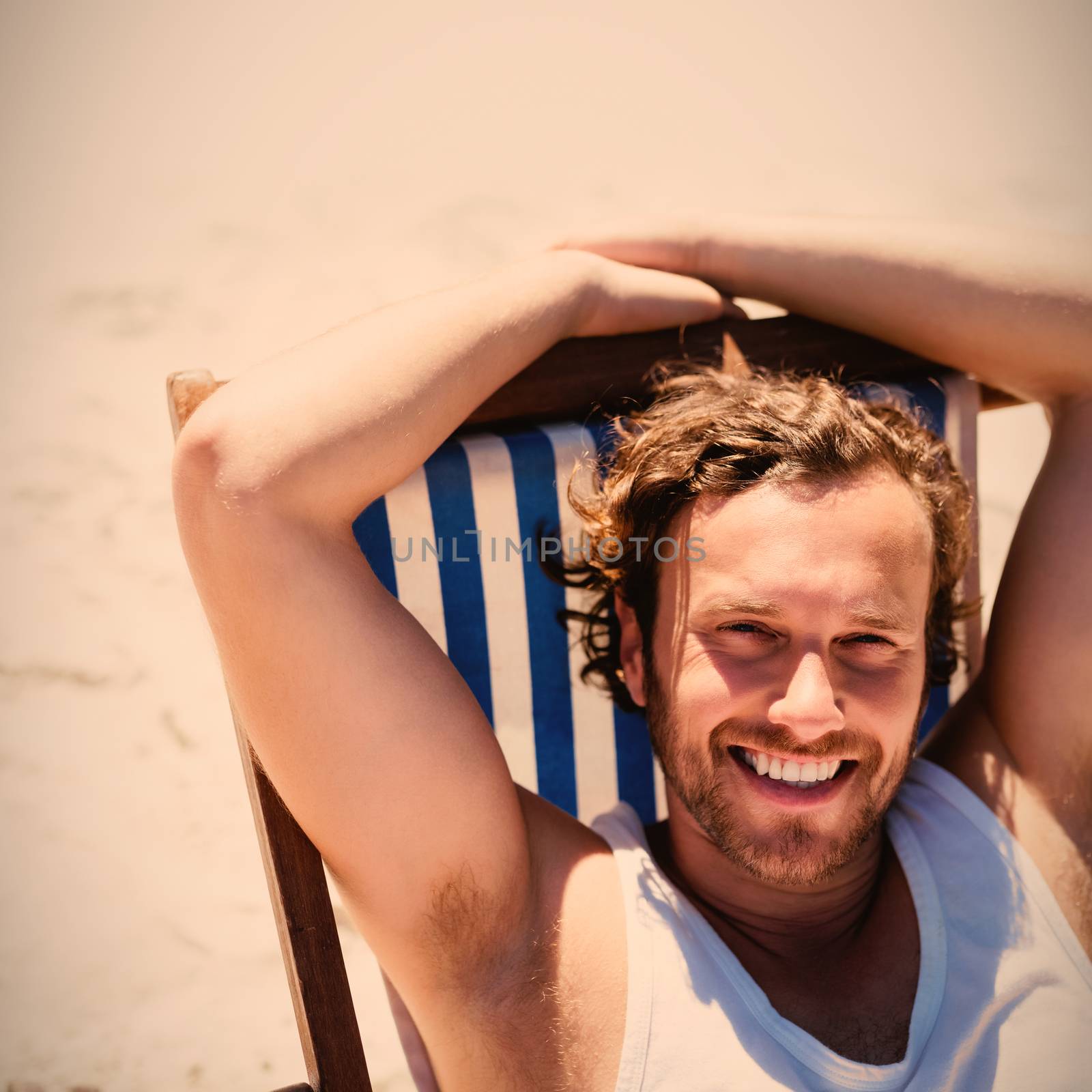 High angle portrait of young woman relaxaing on lounge chair at beach during sunny day