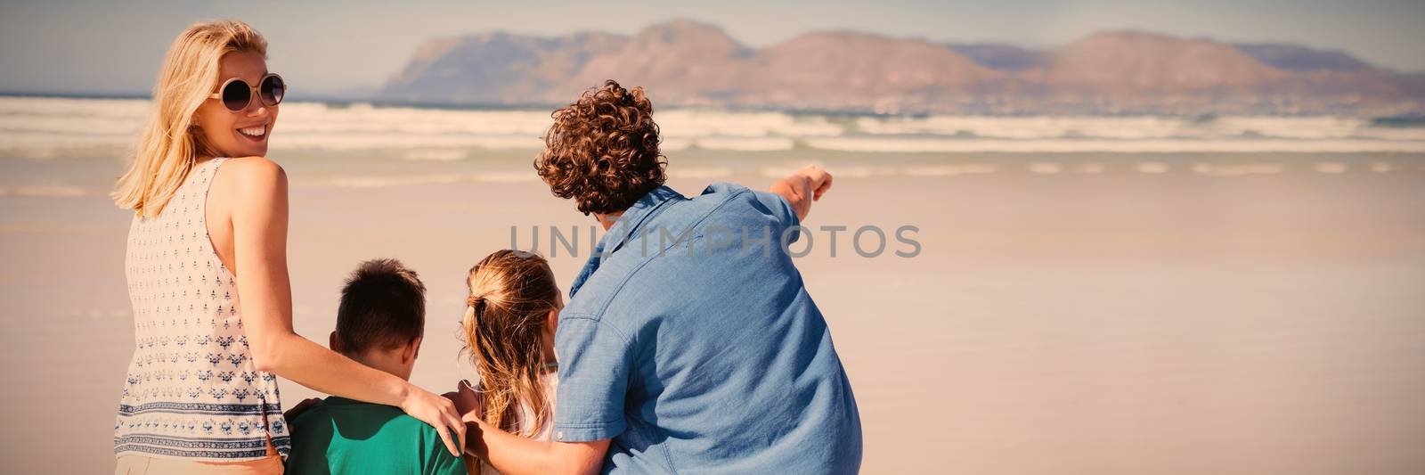 Smiling woman standing with her family at beach by Wavebreakmedia