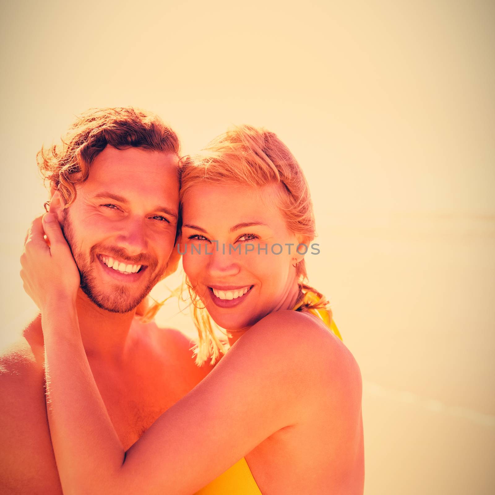 Portrait of smiling couple embracing at beach during sunny day