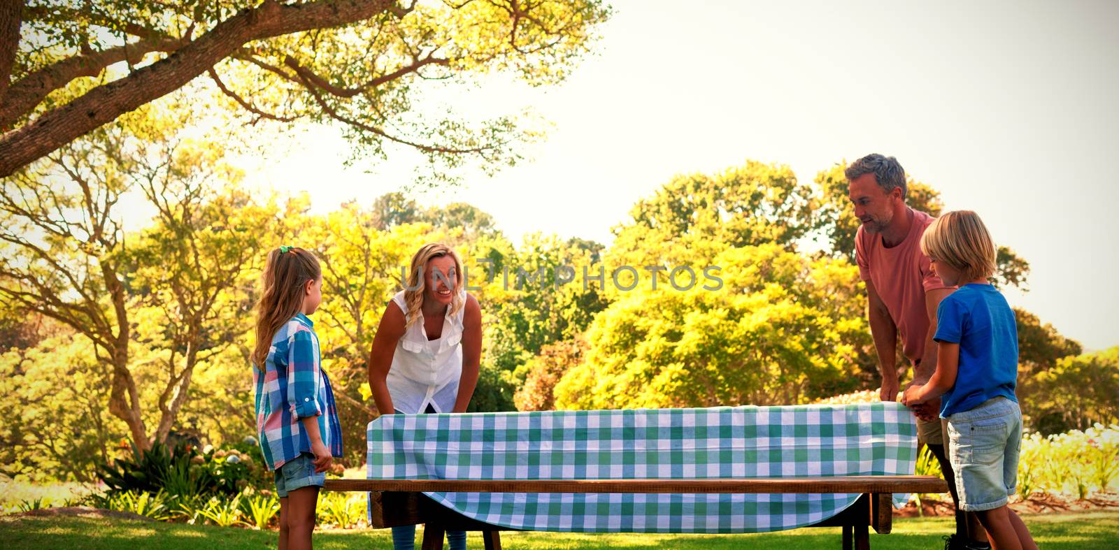 Family spreading the tablecloth on picnic table by Wavebreakmedia