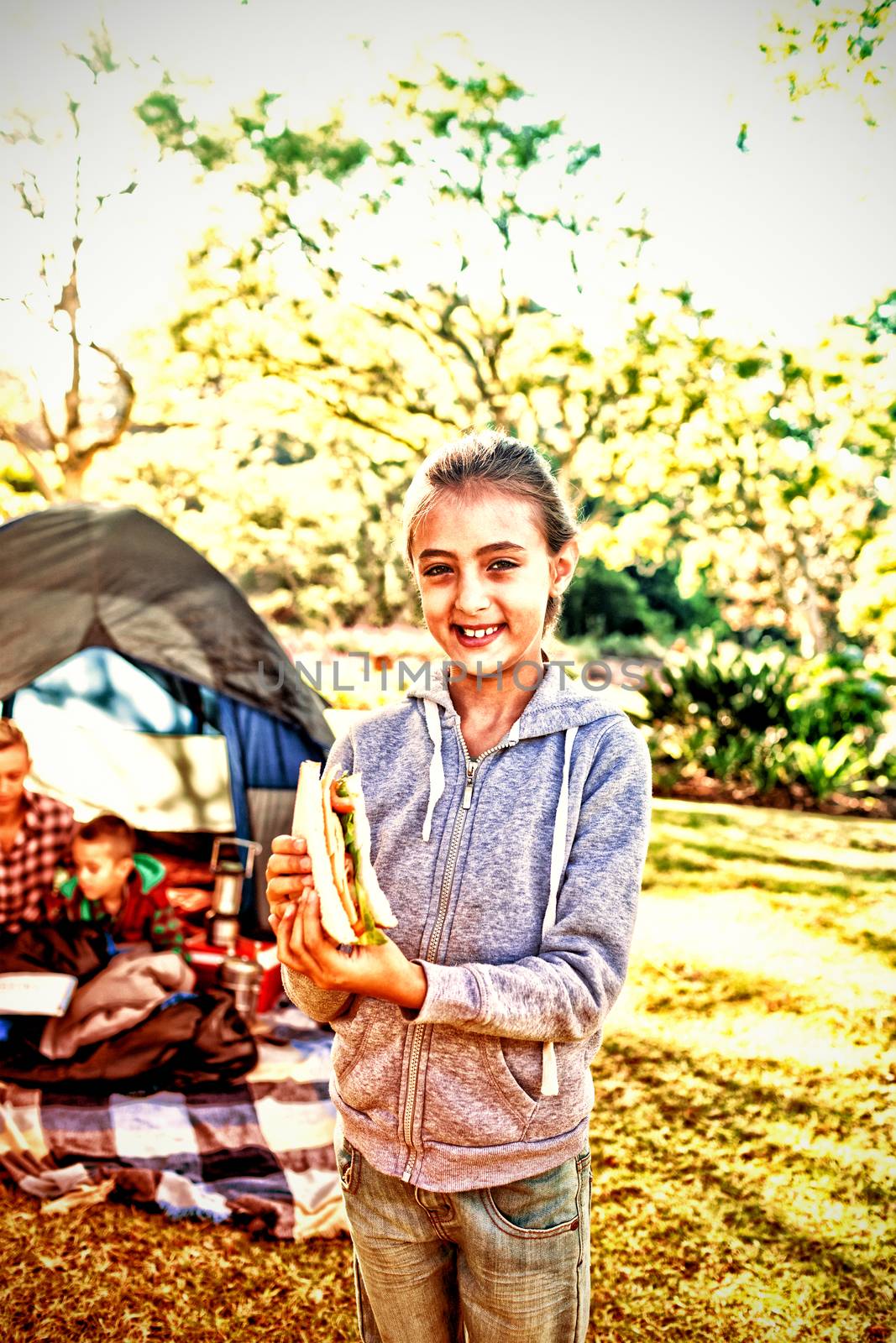 Smiling girl holding a sandwich at campsite by Wavebreakmedia