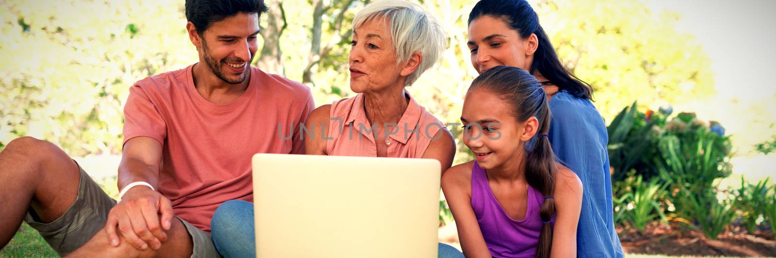 Smiling family talking while using laptop in the park