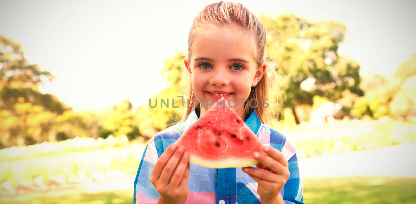 Portrait of smiling girl holding watermelon slice in the park