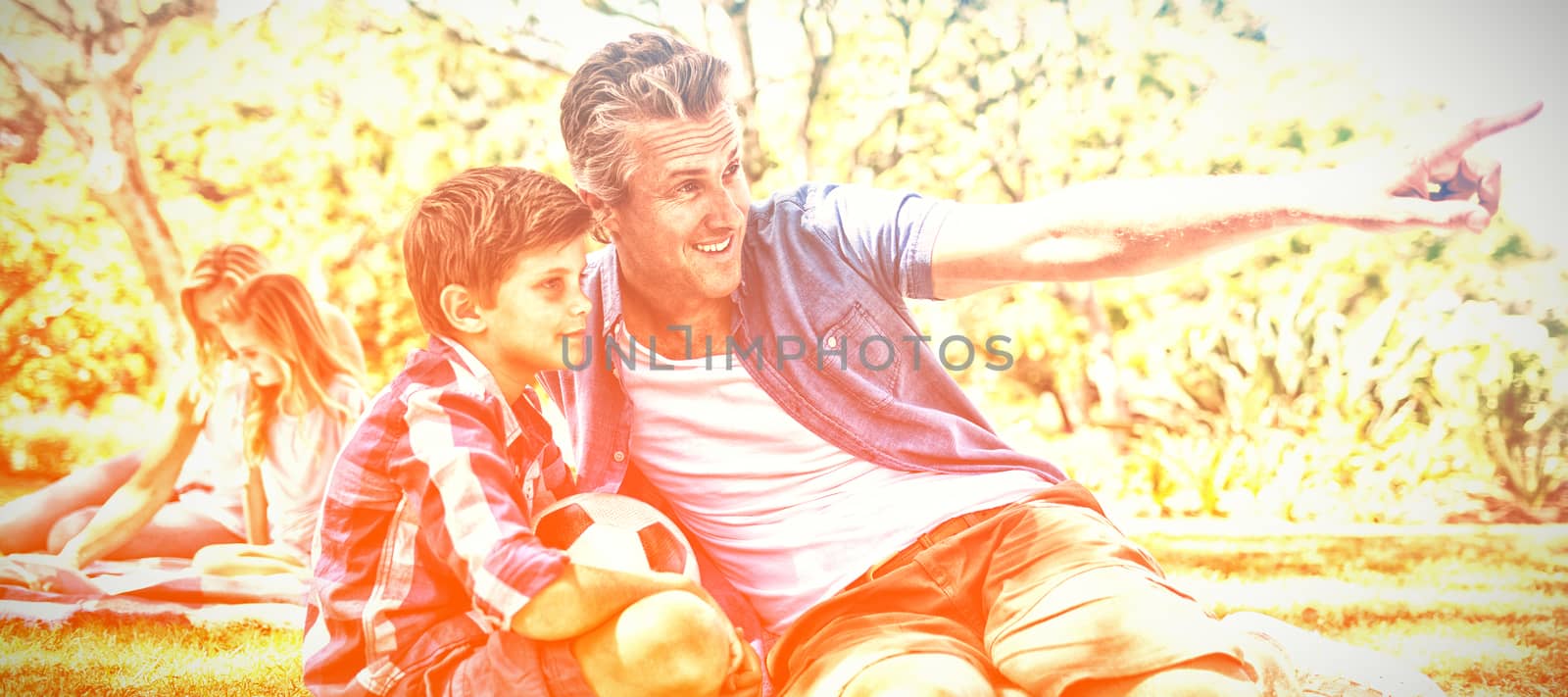 Happy father and son looking at the distance in park on a sunny day