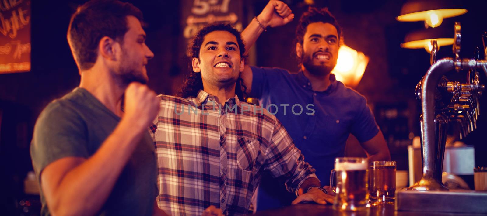 Group of male friends watching football match in pub 