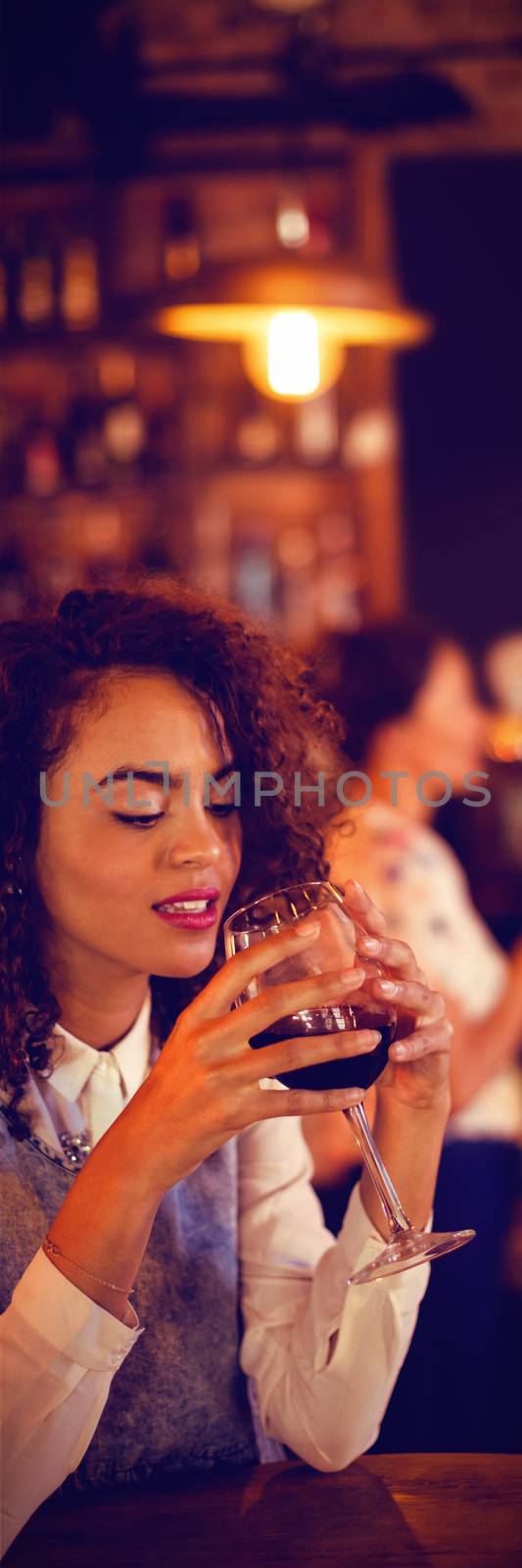 Beautiful young woman having red wine in pub