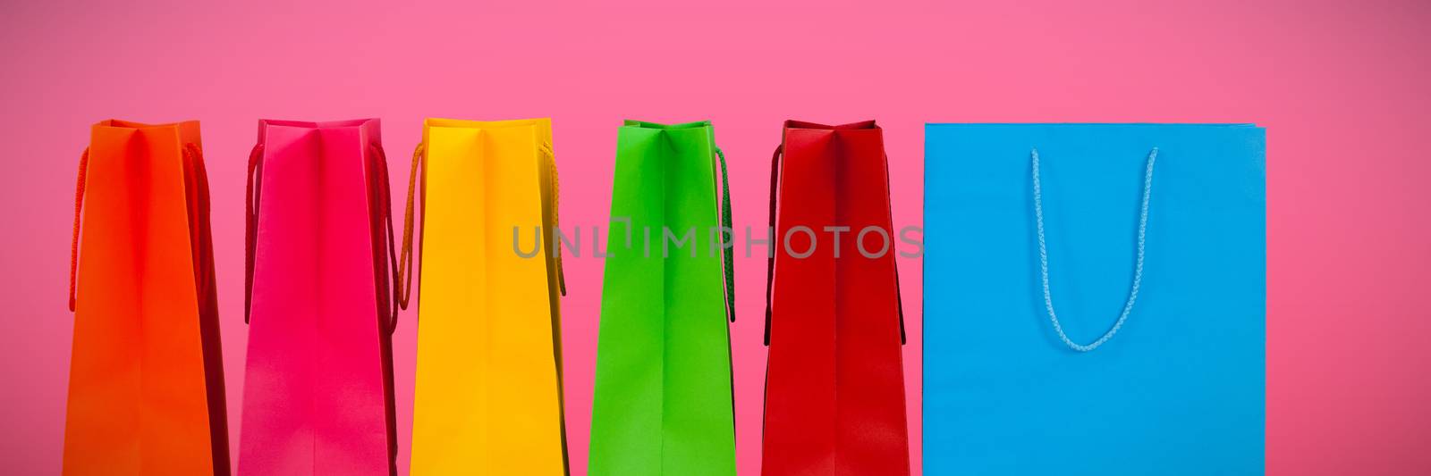 Shopping bags against plain pink background