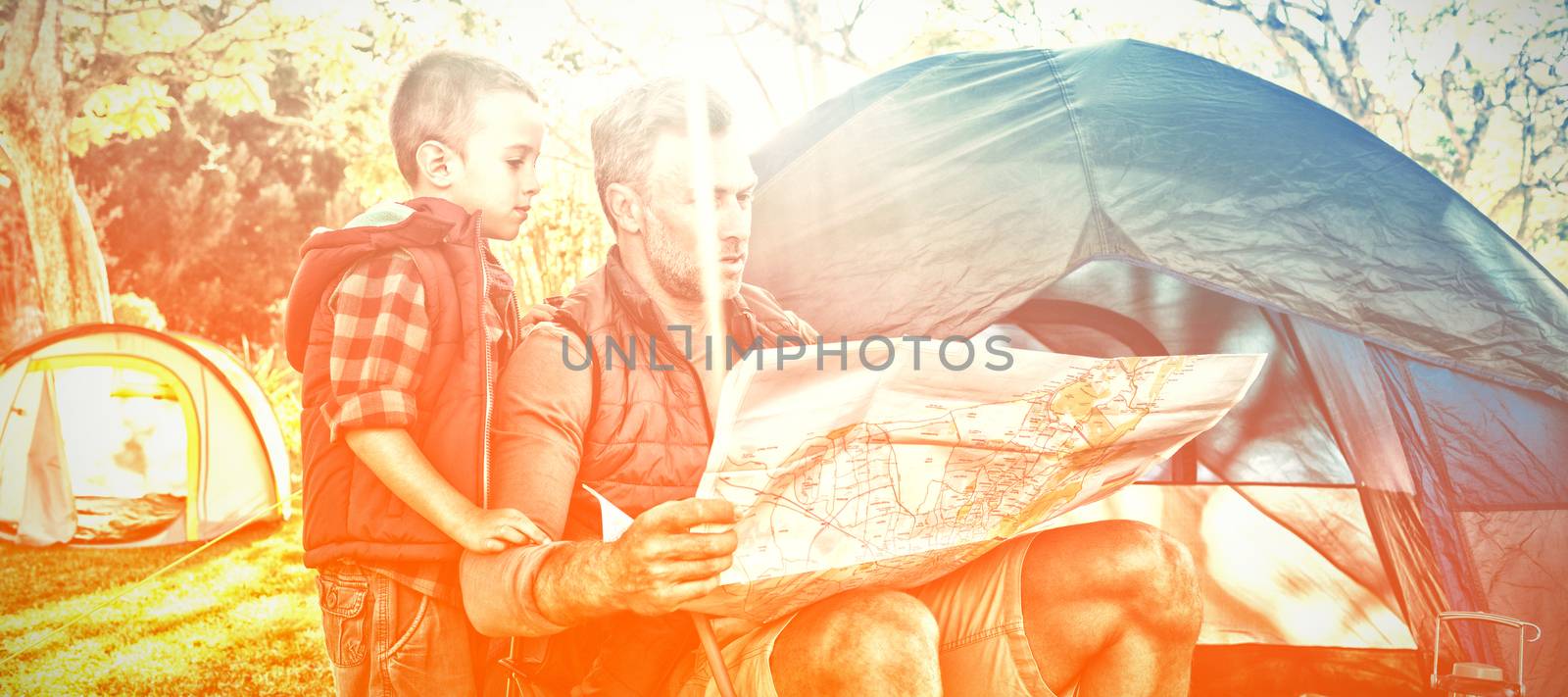 Father and son looking at map outside the tent at campsite