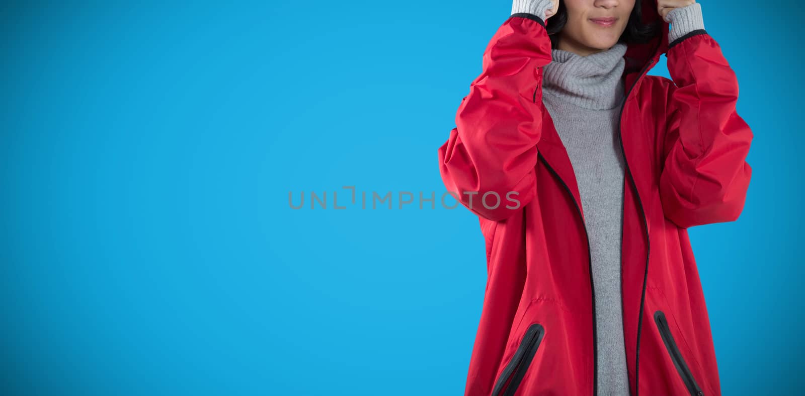 Woman in hooded jacket standing against white background against blue background