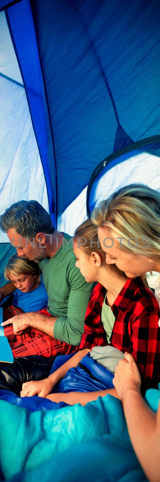 Family reading book together in the tent