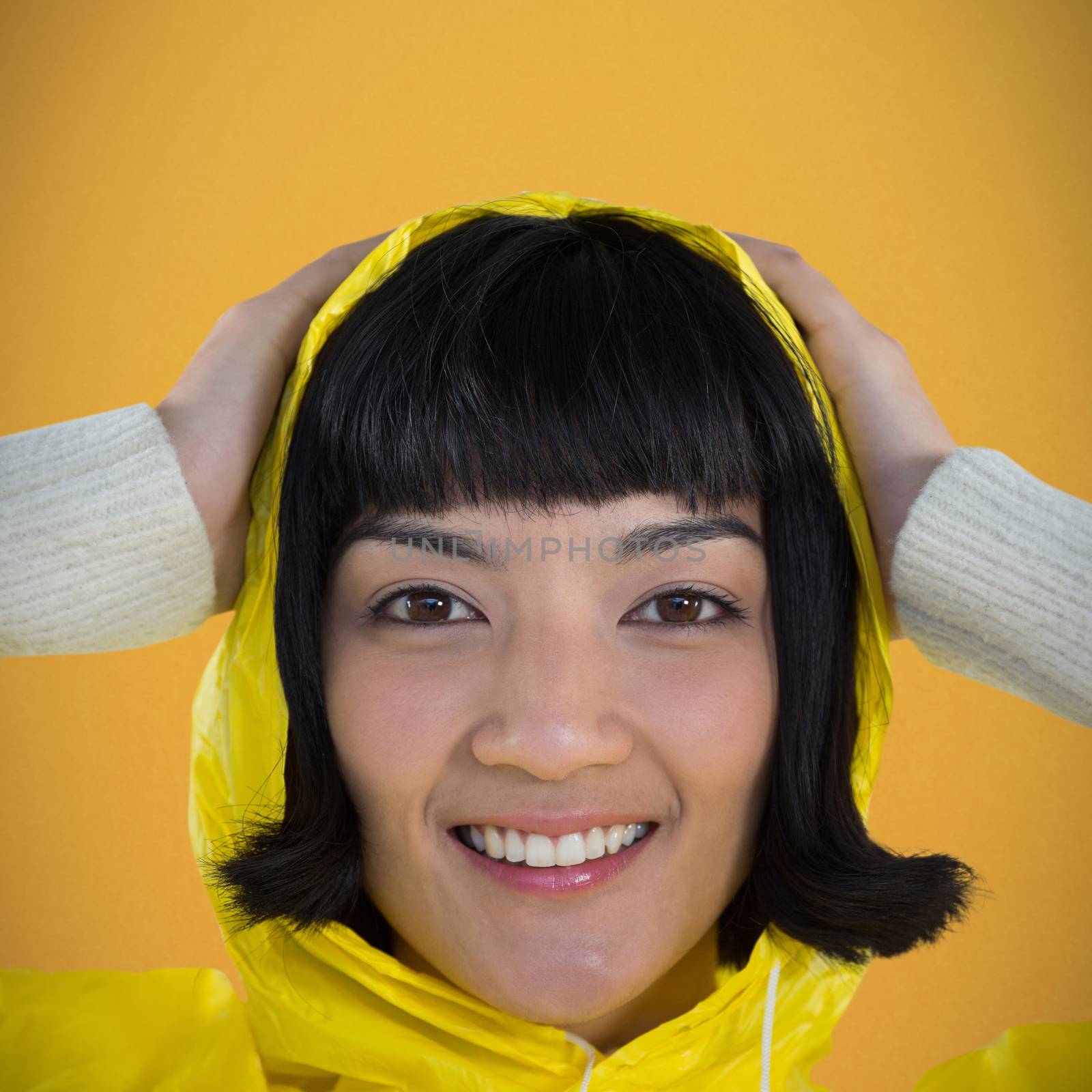 Woman wearing yellow raincoat against white background against orange background