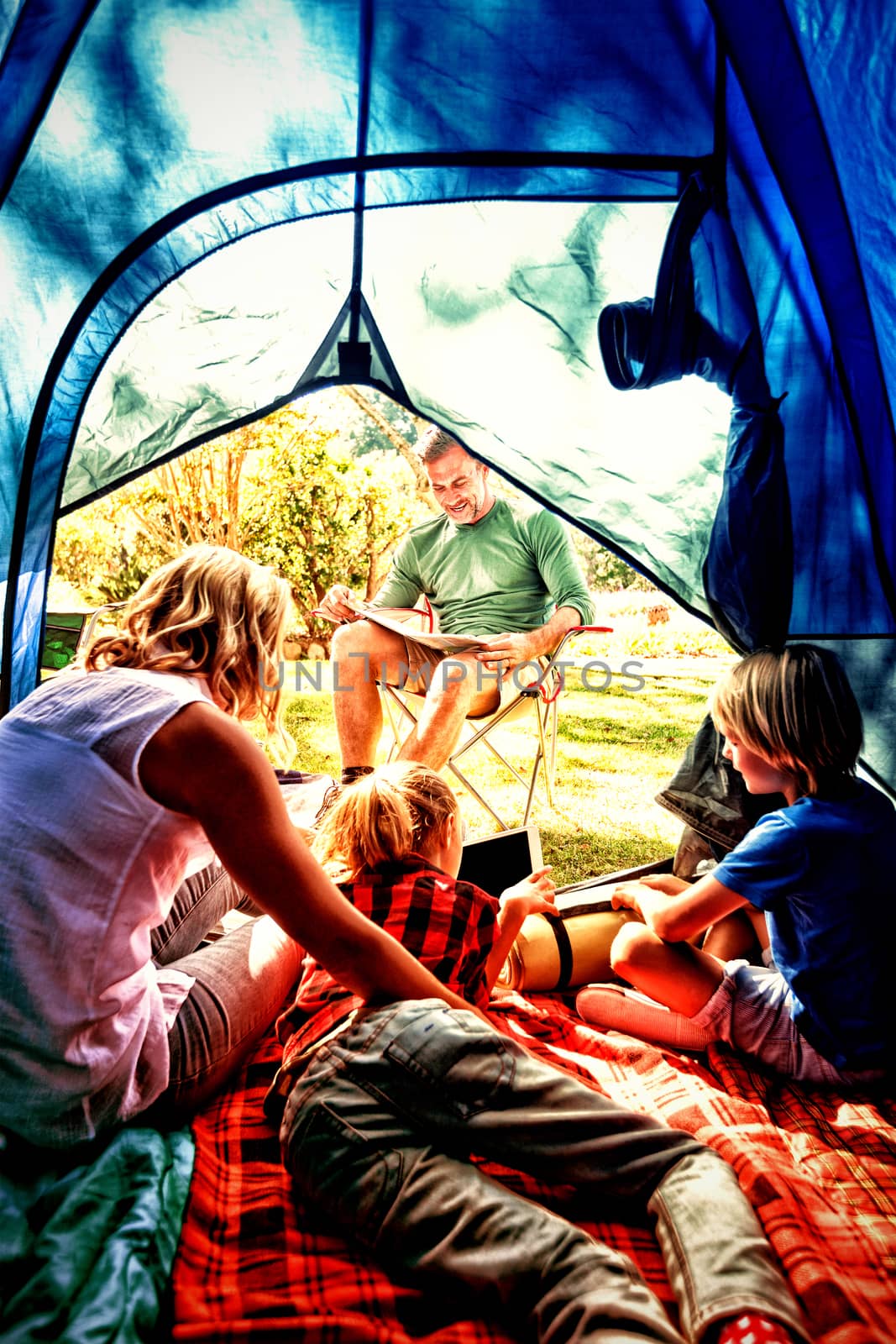 Kids and mother using tablet while father looking at the map at campsite