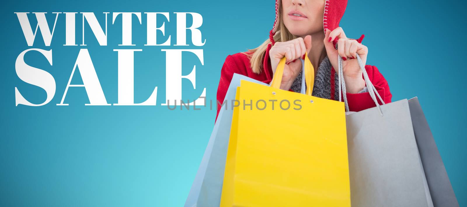 Blonde in winter clothes holding shopping bags against abstract blue background