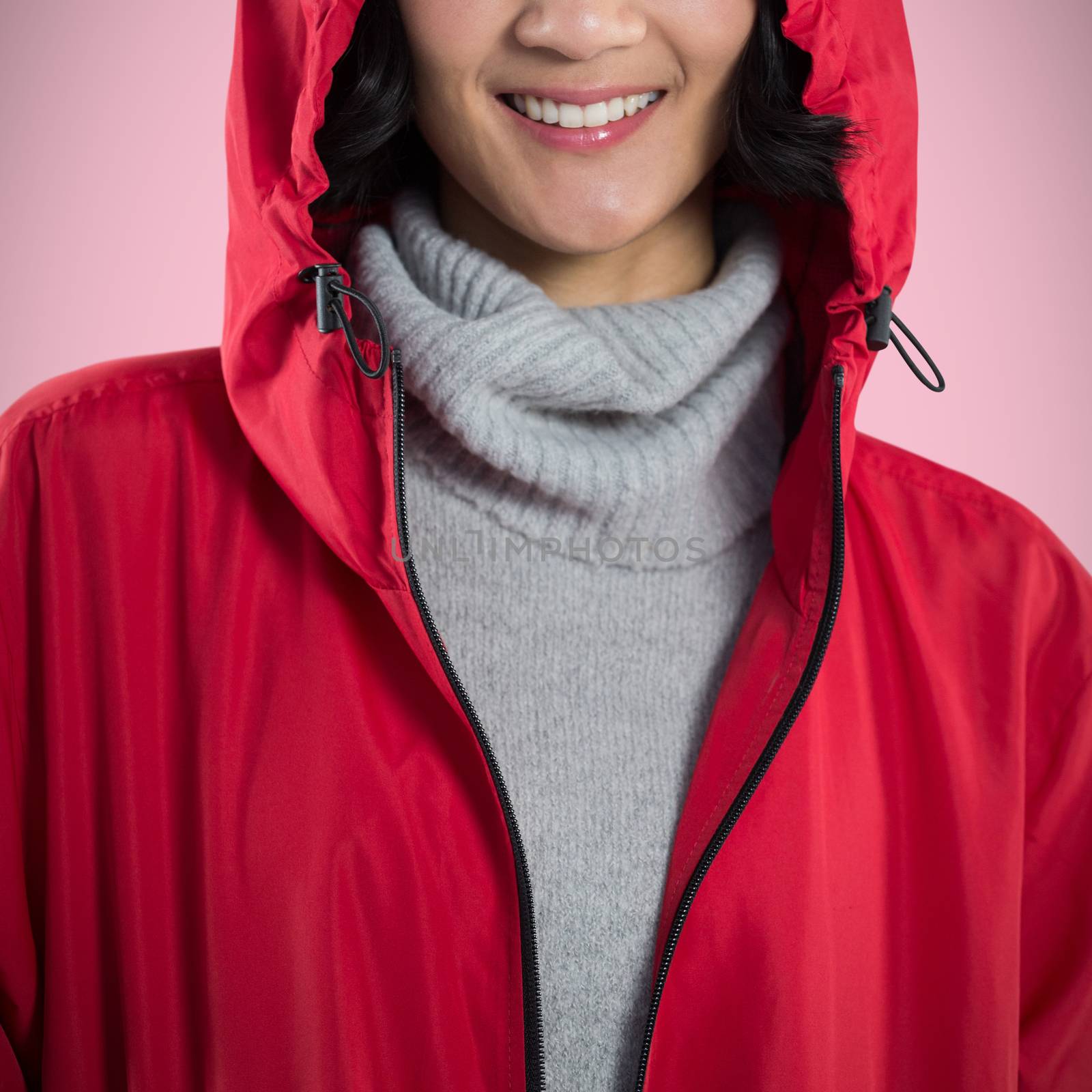 Smiling woman in hooded jacket standing against white background against pink background