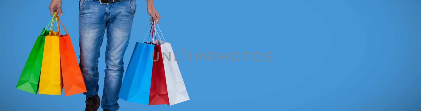 Portrait of young man carrying colorful shopping bag against white background against blue background