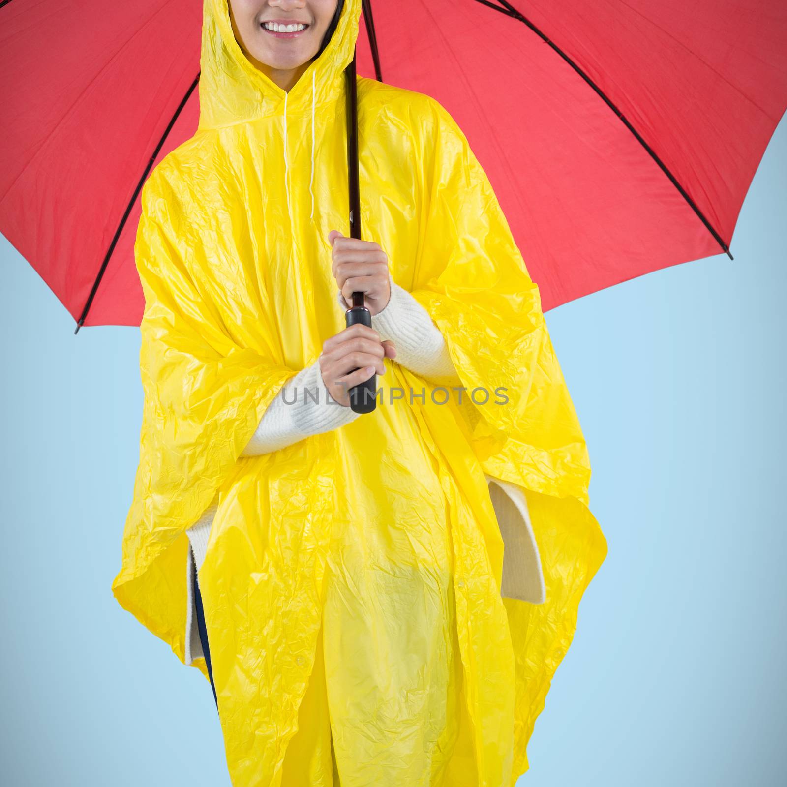 Woman in yellow raincoat holding an umbrella against blue background