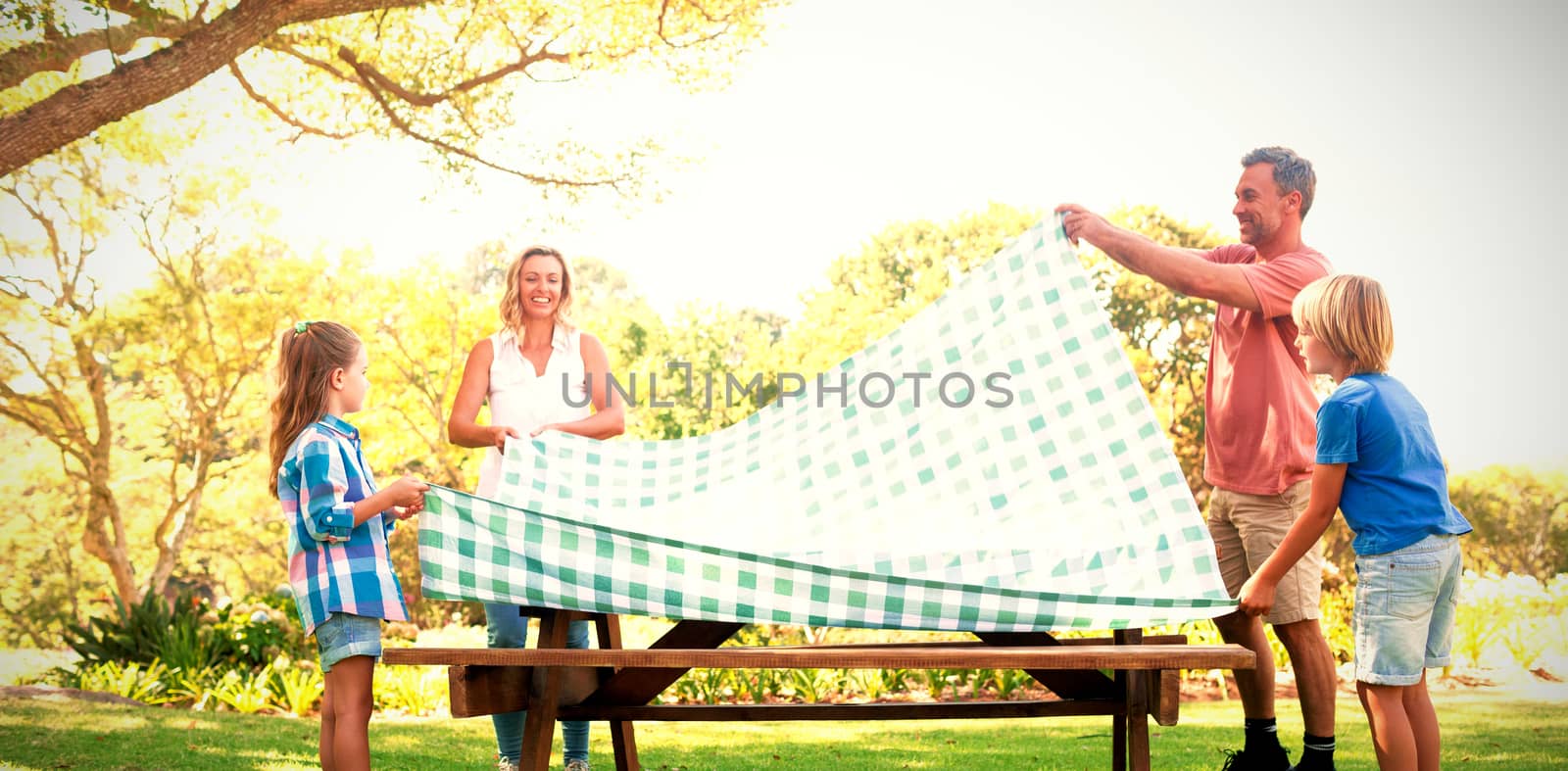 Family spreading the tablecloth on picnic table in park