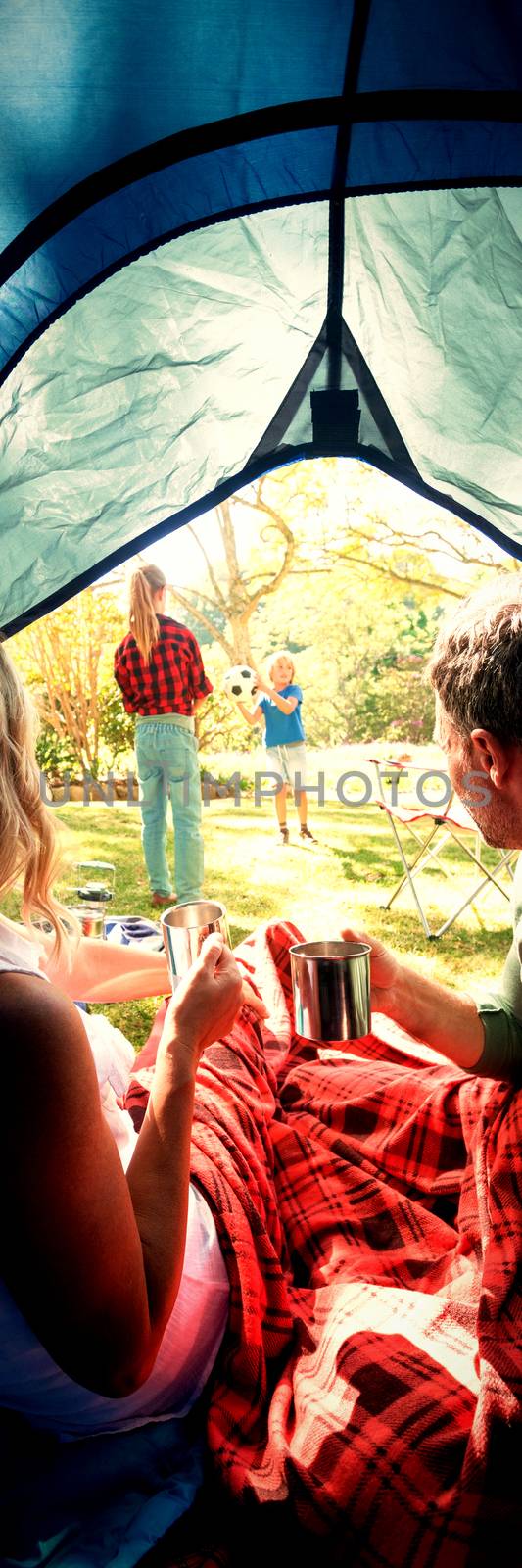 Couple having coffee and looking at kids playing outside the tent by Wavebreakmedia