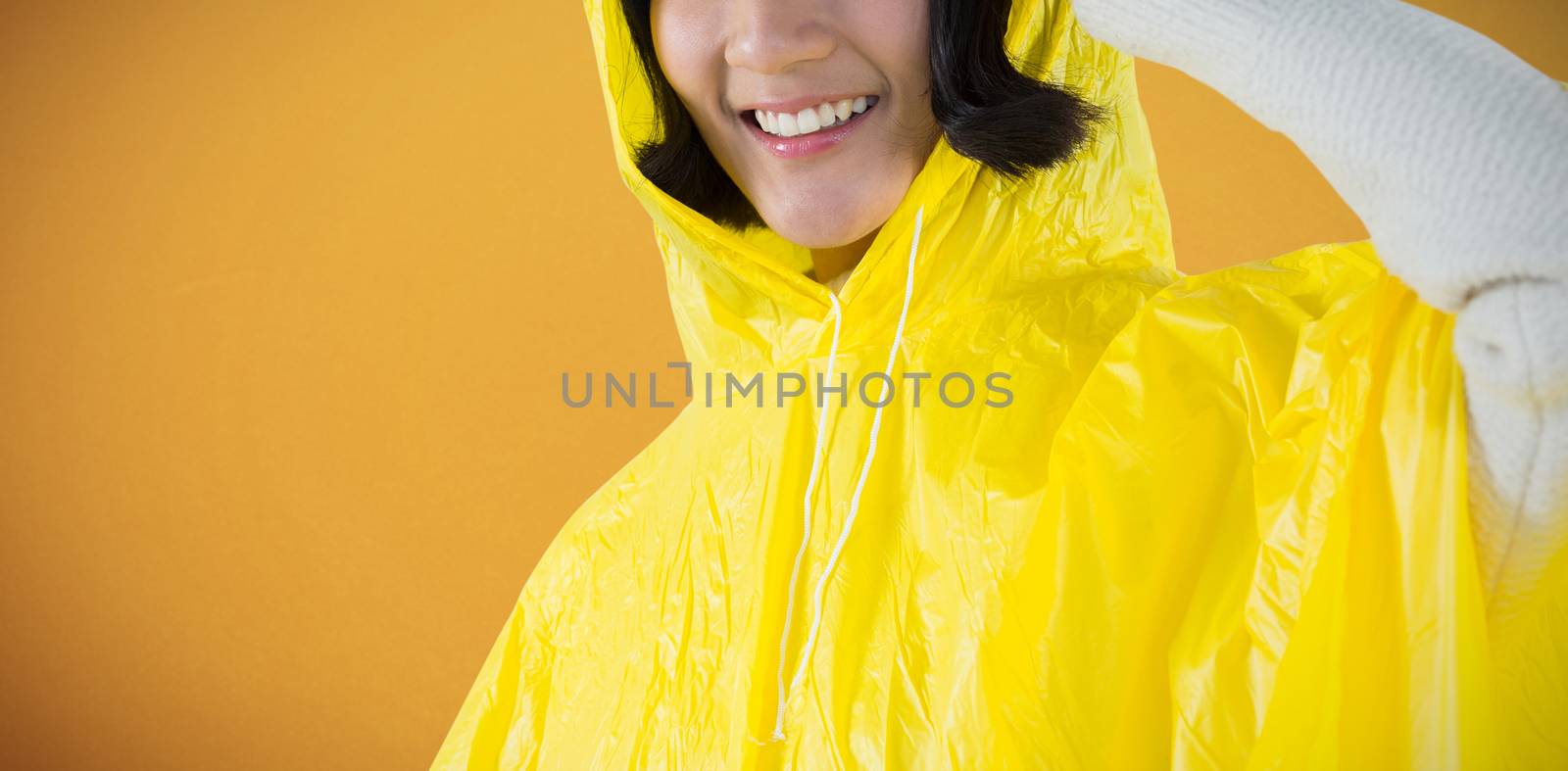 Woman wearing yellow raincoat against white background against orange background